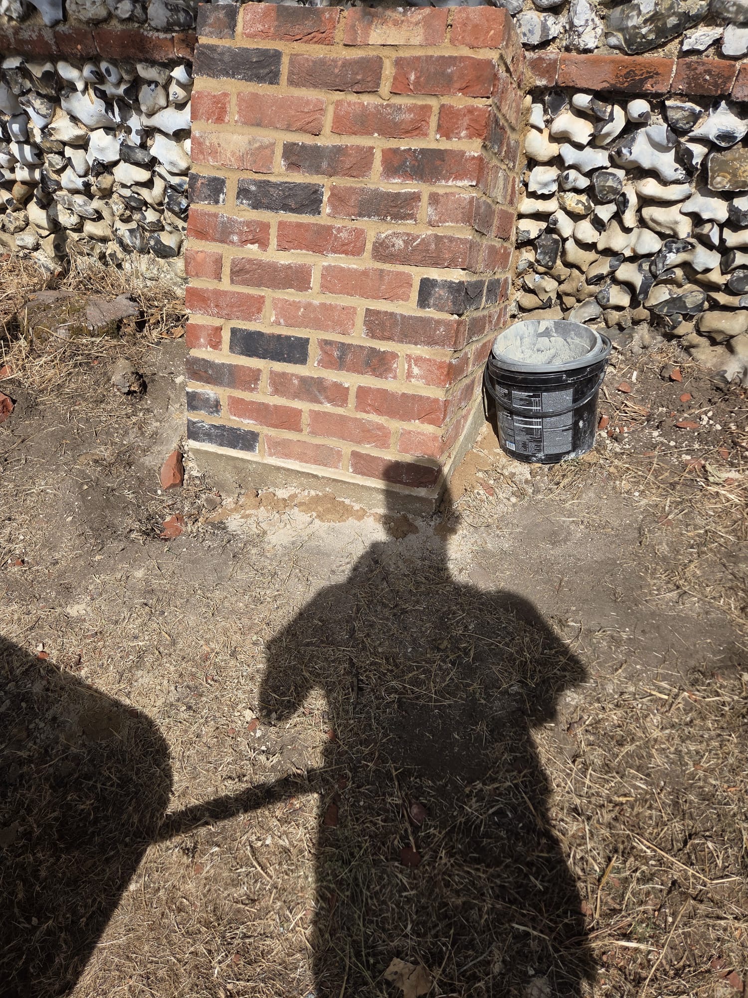 Completed brick pier finished flush with traditional flint walling